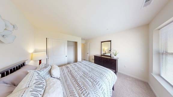 A bedroom with a large bed and a dresser with a mirror.