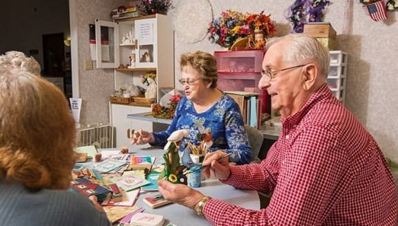 an older man and woman sitting at a table playing with toys