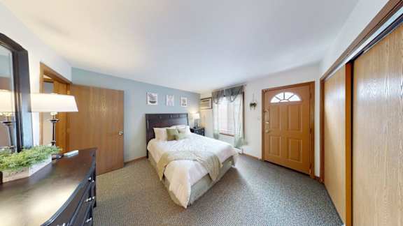 A bedroom with a large bed and a wooden headboard.