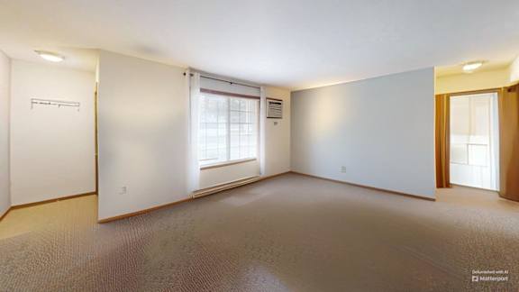 A large, empty room with a window and a door on the right side.