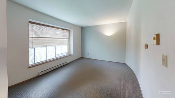 A room with a window and a carpeted floor.