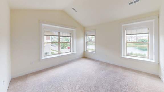 A spacious room with two windows and carpeted floor.