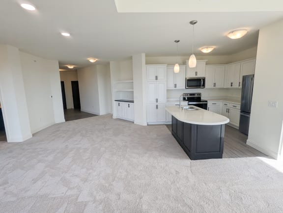 an empty kitchen and living room with white cabinets and a counter top