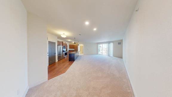 A spacious room with a carpeted floor and a few pieces of furniture.