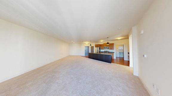 A long, empty room with a carpeted floor and white walls.