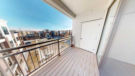 A balcony with a white door and a railing overlooking a cityscape.