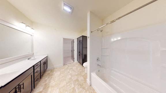 A bathroom with a white tub and a white sink with black cabinets.
