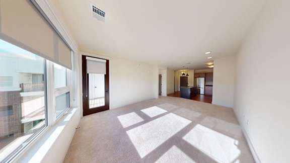 A spacious room with a rug on the floor and a door on the right side.