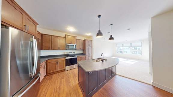 A kitchen with wooden cabinets and a stainless steel refrigerator.