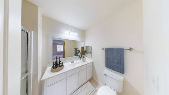 A white bathroom with a towel hanging on the wall.