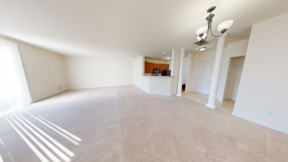 an empty living room and kitchen with white walls and carpet