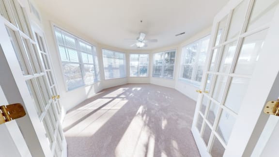 a sun room with windows and a ceiling fan