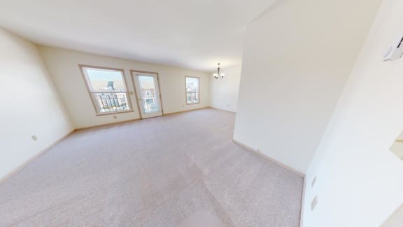 the living room and dining room of an empty home with white walls and carpet