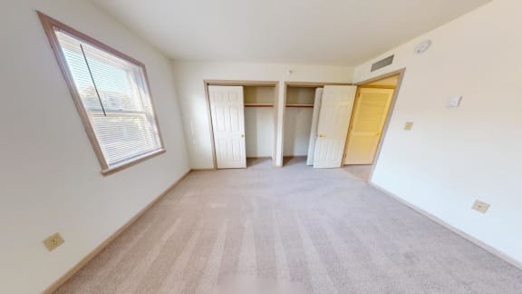 an empty living room with a large window and a closet