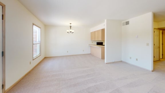 an empty living room and kitchen with a window