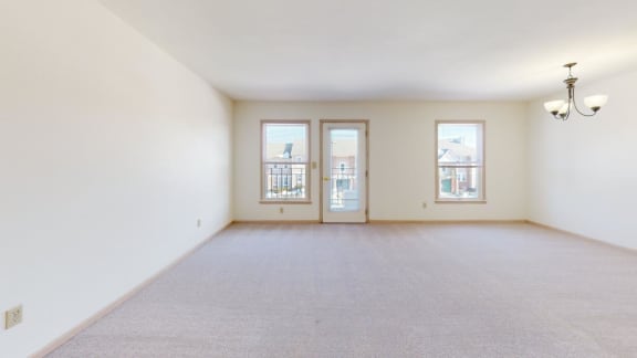 an empty living room with two doors and a carpeted floor