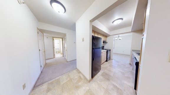 a renovated living room and kitchen with a black refrigerator