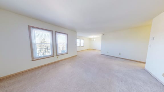 the living room and dining room of an empty home with large windows