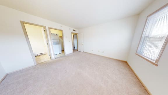 the living room and bedroom of an apartment with white walls and carpet
