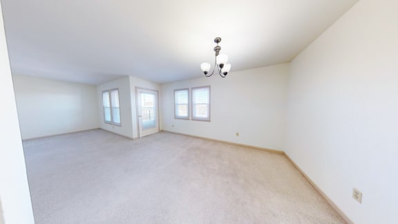 the living room and dining room of an empty home with white walls and carpet