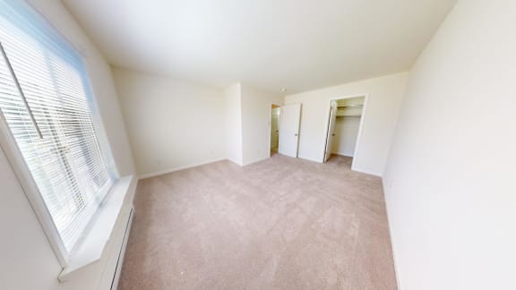 a spacious living room with a large window and carpet