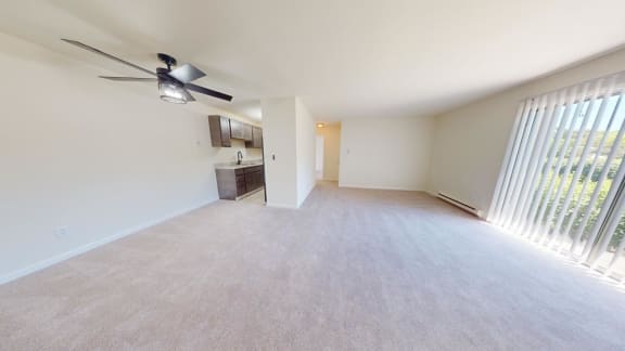 an empty living room with a ceiling fan and a window