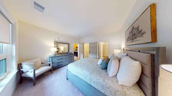 A bedroom with a bed, dresser, and chair.