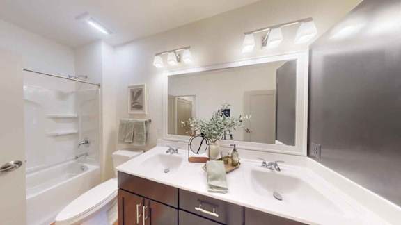 A bathroom with a white sink and a large mirror.