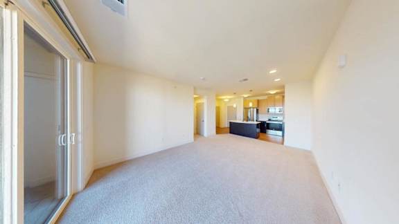 A spacious room with a carpeted floor and a sliding glass door.