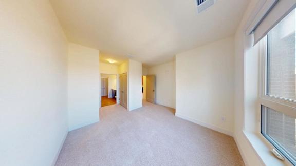 A long, empty hallway with a carpeted floor and white walls.