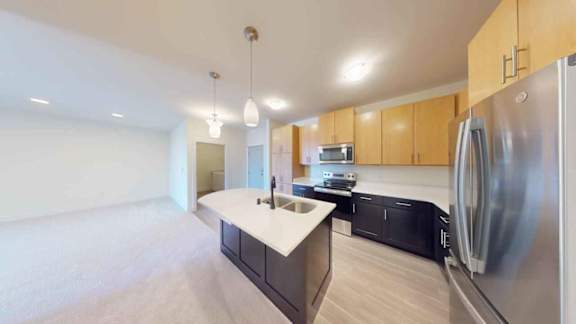 A modern kitchen with a stainless steel refrigerator and wooden cabinets.