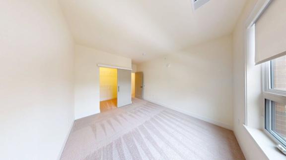 A room with a carpeted floor and a window on the right side.