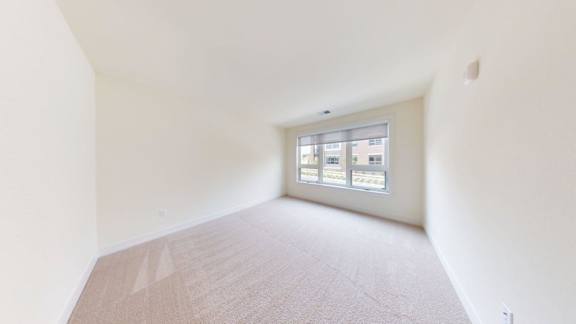 A room with a window and a carpeted floor.