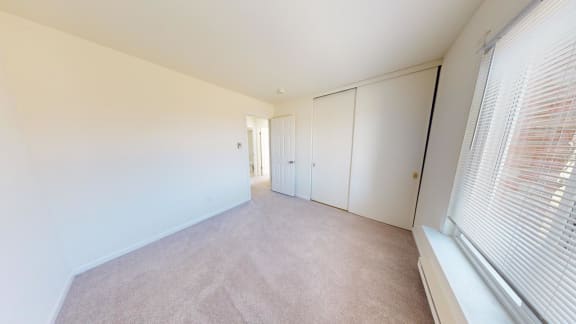 a bedroom with a large window and white walls