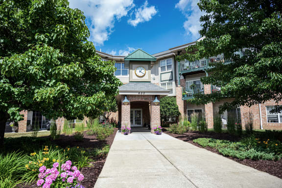 a sidewalk in front of a brick building with a clock on the front