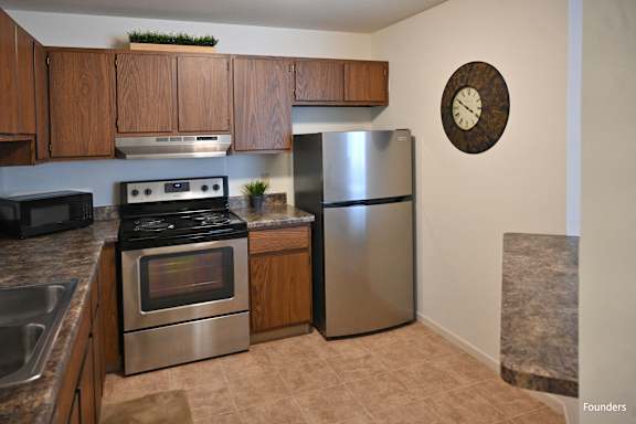 A kitchen with a stove, refrigerator, and microwave.