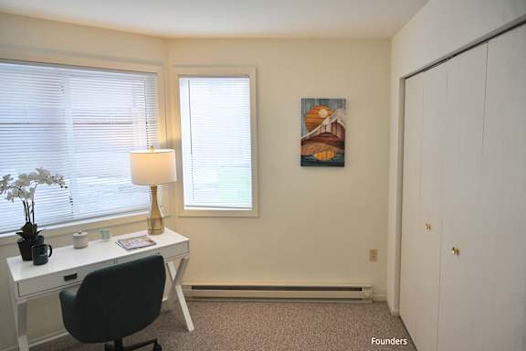 A room with a desk, chair, and a painting on the wall.