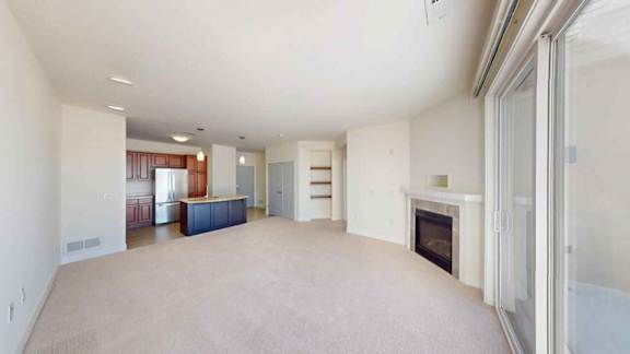 A spacious living room with a fireplace and a dining area in the background.