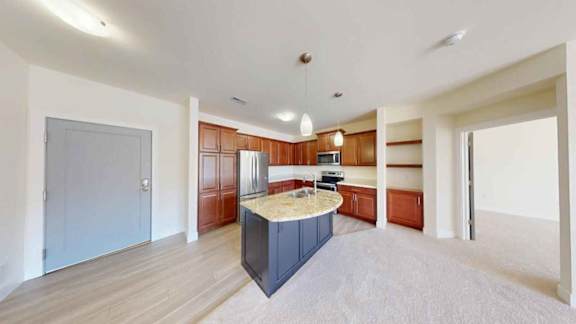 A kitchen island with a countertop and a sink is in the middle of a spacious room with wooden floors and white walls.