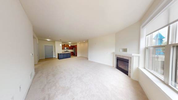 A large, empty room with a fireplace and a window.