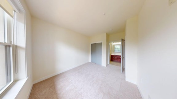 A room with a carpeted floor and a window on the left side.