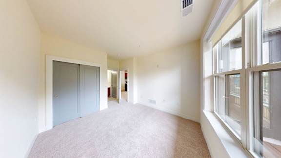 A room with a carpeted floor and a large window on the right side.