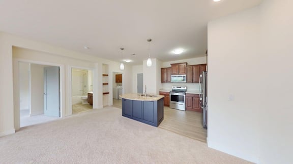 A spacious living room with a kitchen in the background.