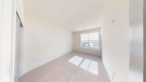 A room with a carpeted floor and a window.