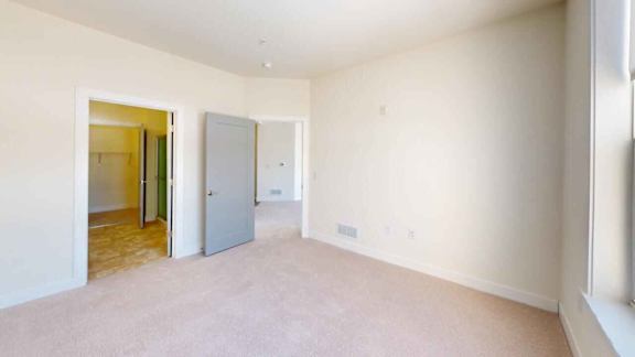 A room with a carpeted floor and a doorway leading to another room.