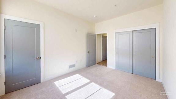 Three doors are in a room with white walls.