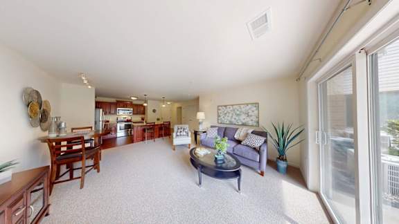 A living room with a couch, coffee table, and a dining table.