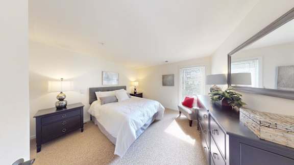 A bedroom with a bed, nightstand, and a window.