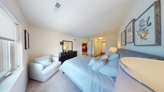 A bedroom with a bed, a chair, and a dresser.
