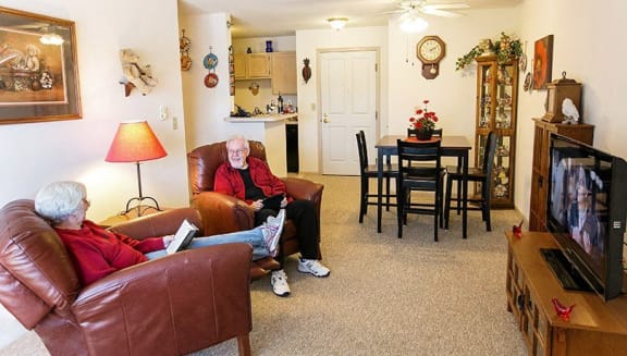 two people sitting in a living room watching tv